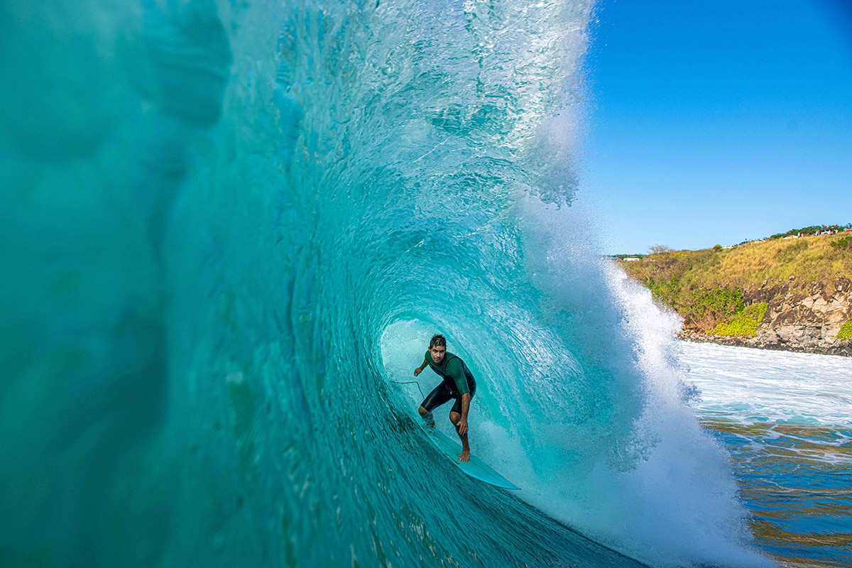 Surfer riding inside a turquoise wave barrel