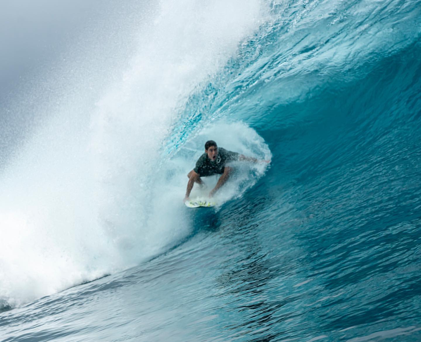 Surfer carving a blue-green wave
