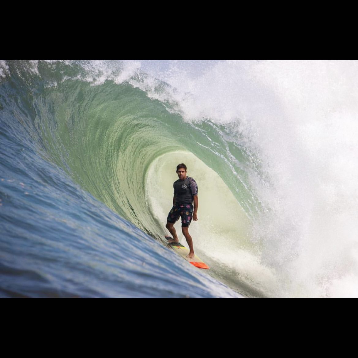 Surfer riding beneath a breaking barrel